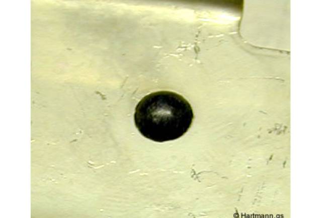 Ein Blech-Stanzteil wird durch einen heißverstemmten Pin in seiner Position fixiert.